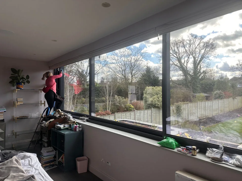 Cleaning the inside of a full-width picture window from a stepladder