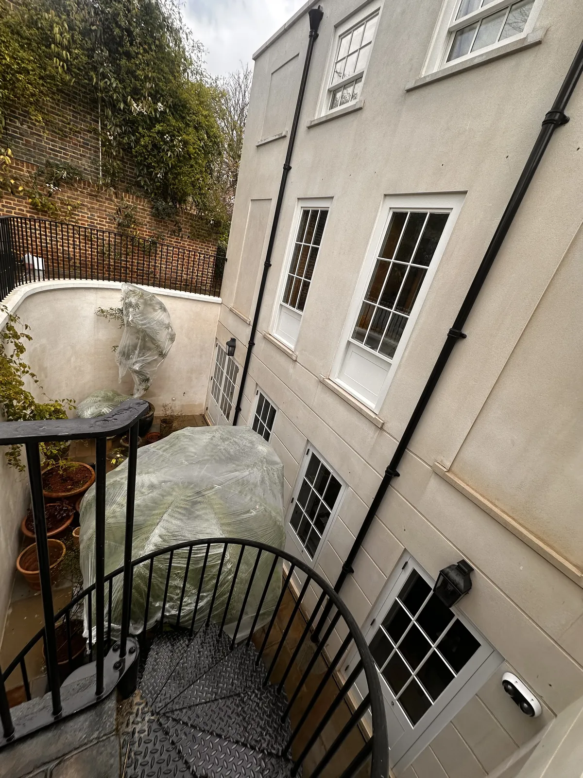 Clean stucco walls and stone paving in the lightwell of a London townhouse