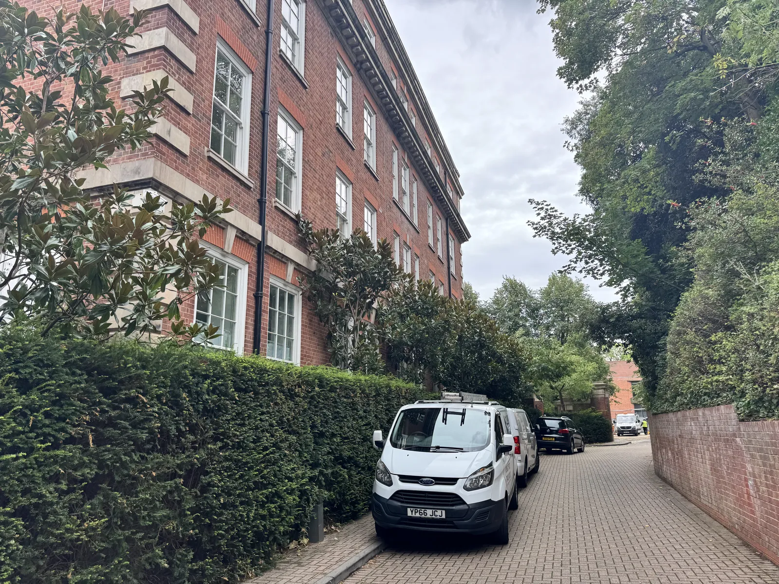 The Clarity Property Care van on a leafy private road beside a red brick mansion block